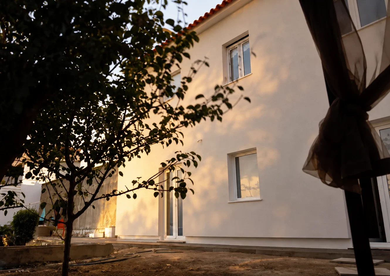 EN09 Mafra – white rear façade of the rehabilitated house in the evening light, seen from the garden